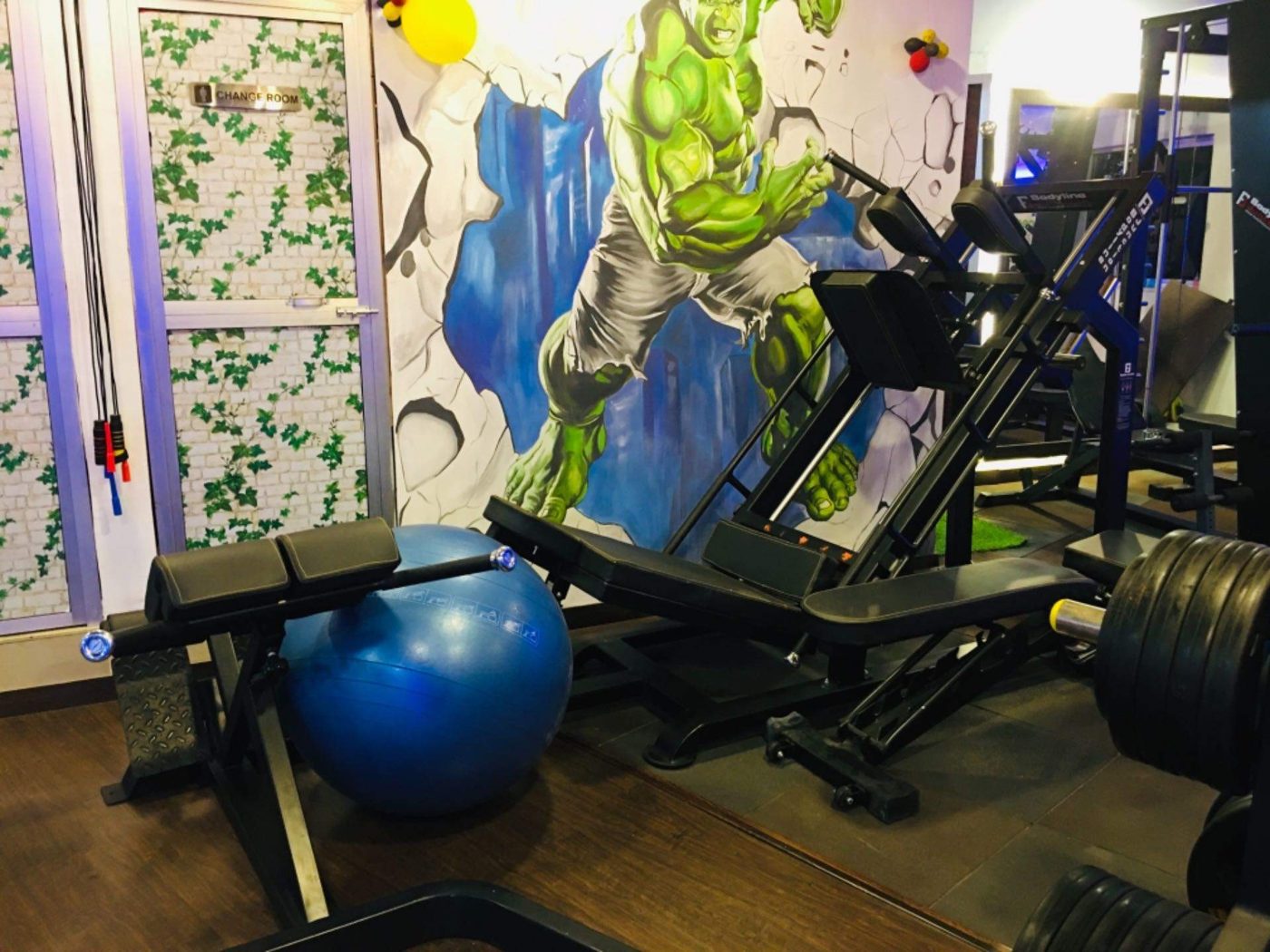Hulk mural with a stability ball, benches and a leg press