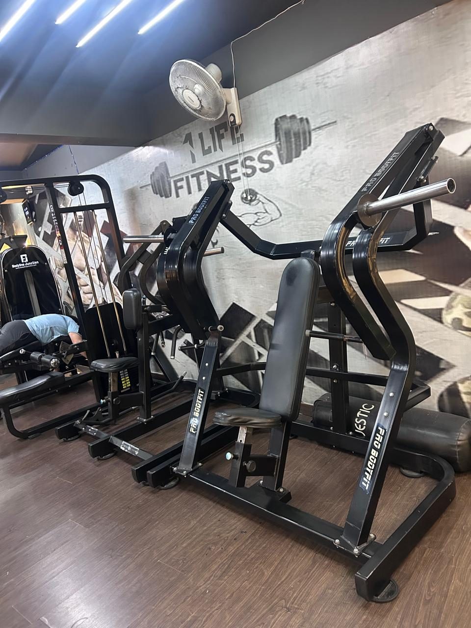 Plate-loaded machines in front of the 1 Life Fitness wall logo