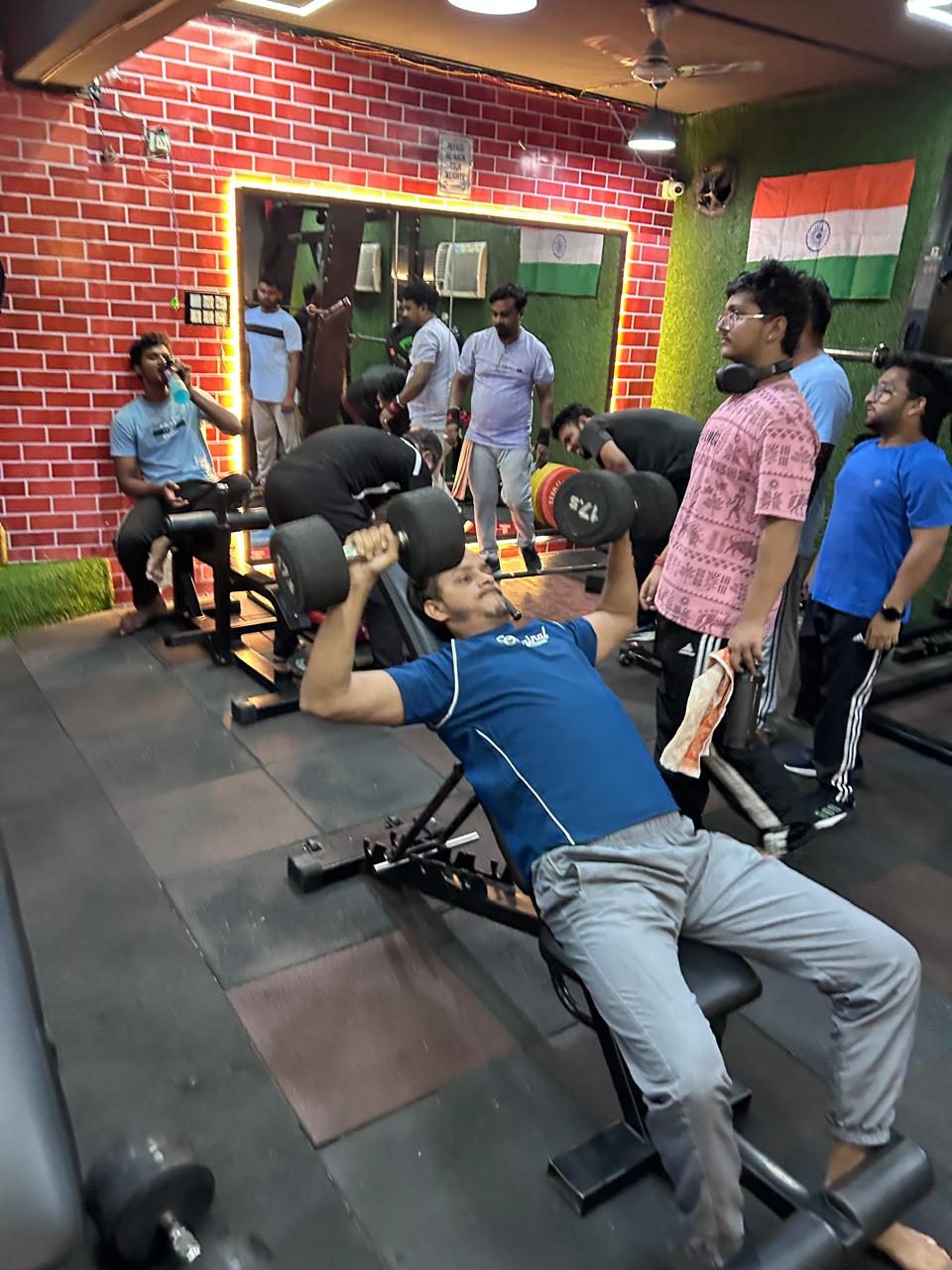 Member doing an incline dumbbell press while others train behind him