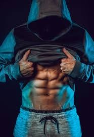 Athlete lifting a hoodie to show defined abs